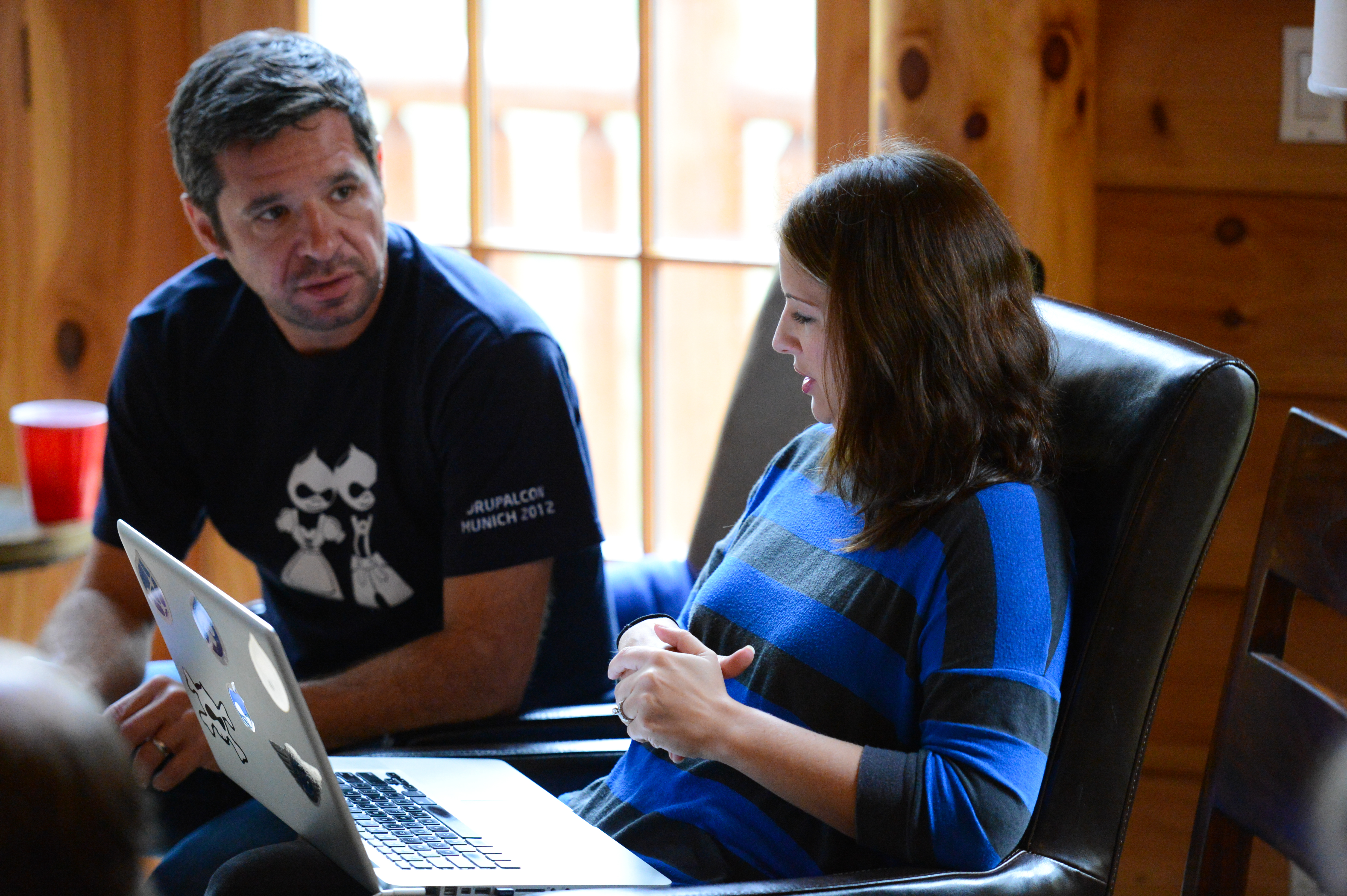 Two people sitting indoors, engaged in conversation.