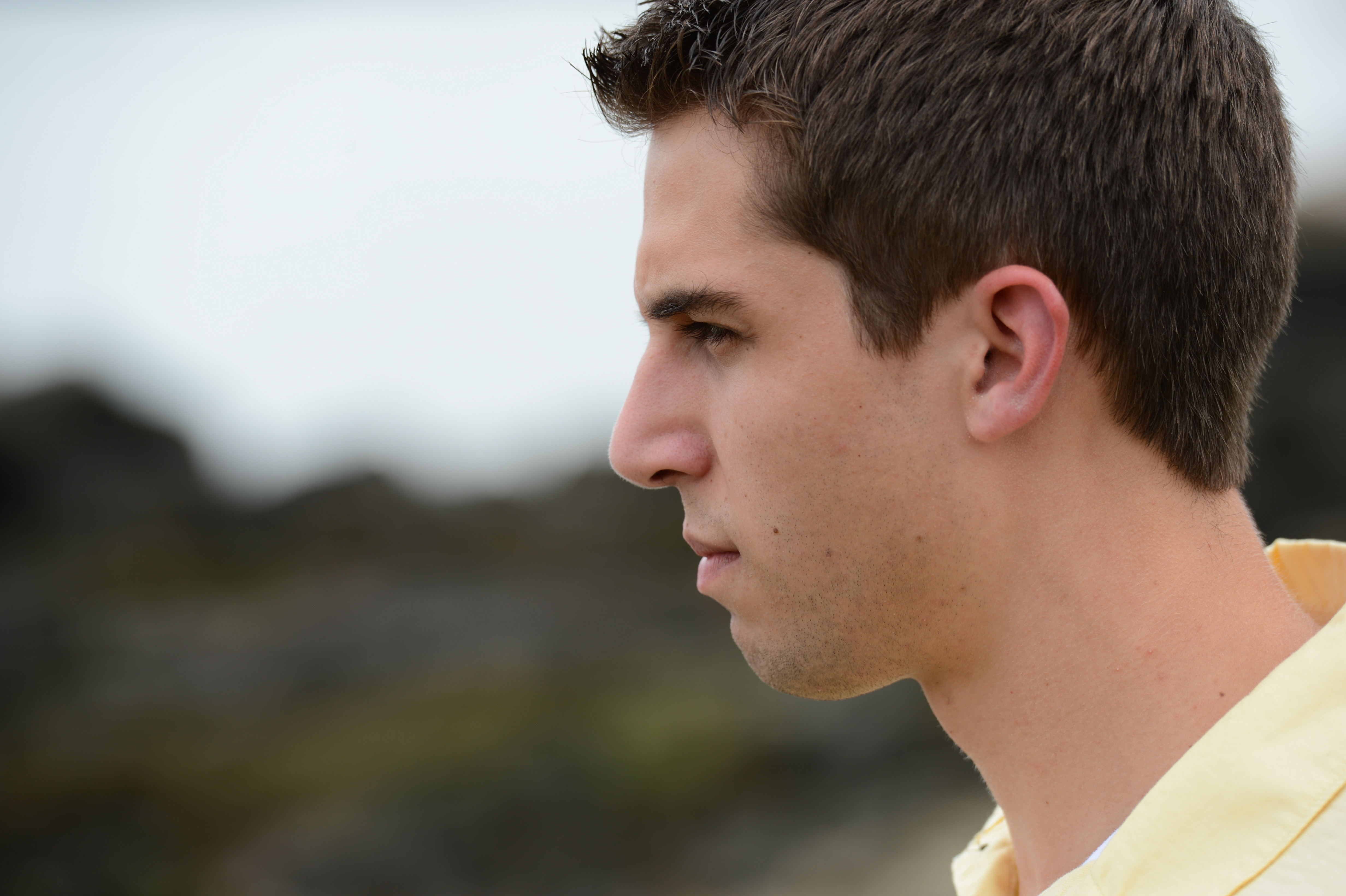 A person in a yellow shirt looks to the side with a serious expression.