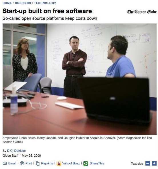 Three employees discuss in a conference room, with a whiteboard covered in notes behind them.