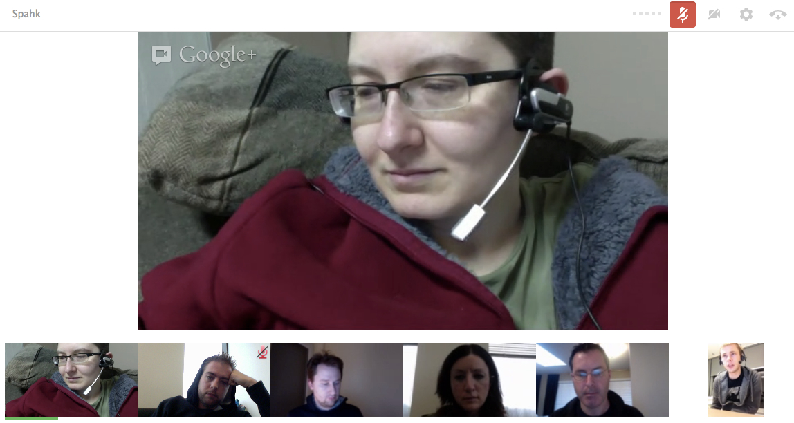 A person wearing a headset participates in a video call with five others, appearing focused on the discussion.
