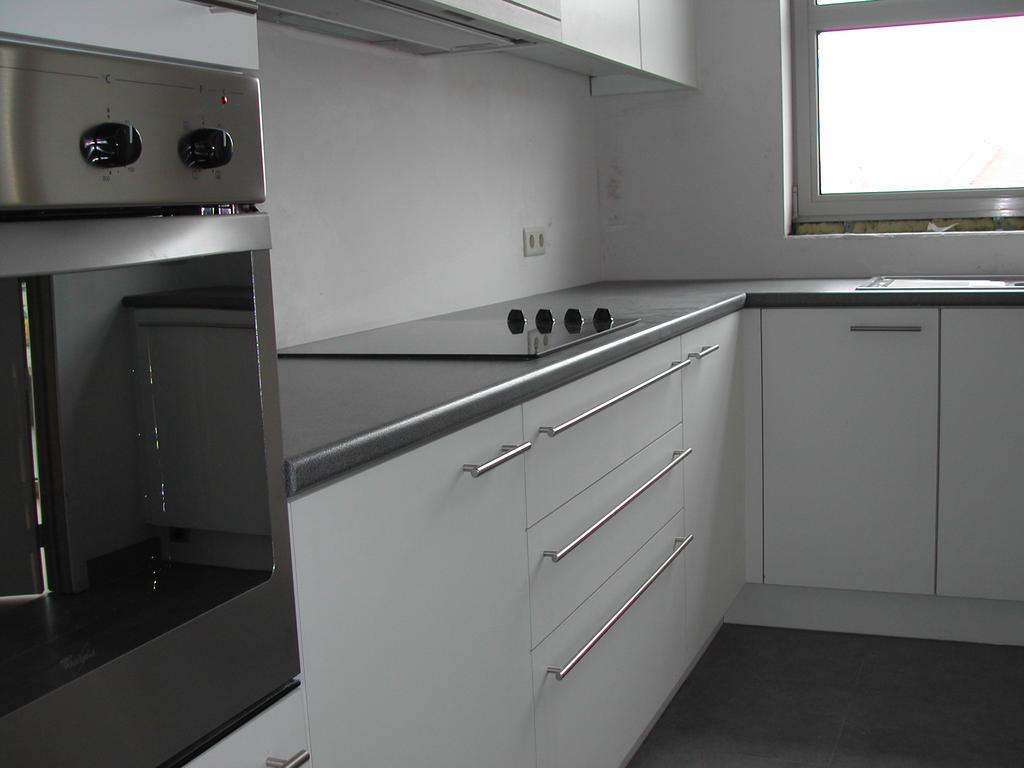 Modern kitchen with white cabinets, black countertops, built-in oven, and stovetop, photographed before move-in in March 2003.