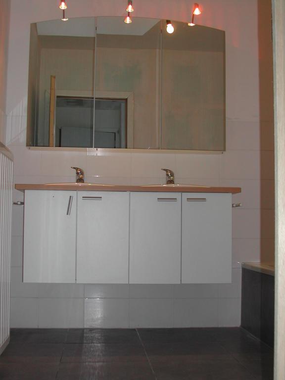 A large bathroom with a double sink vanity, mirrors, and overhead lighting.