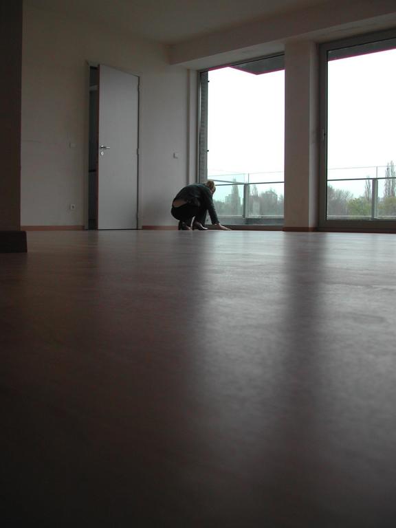 A person crouches near a large window in an empty living room before moving in March 2003.