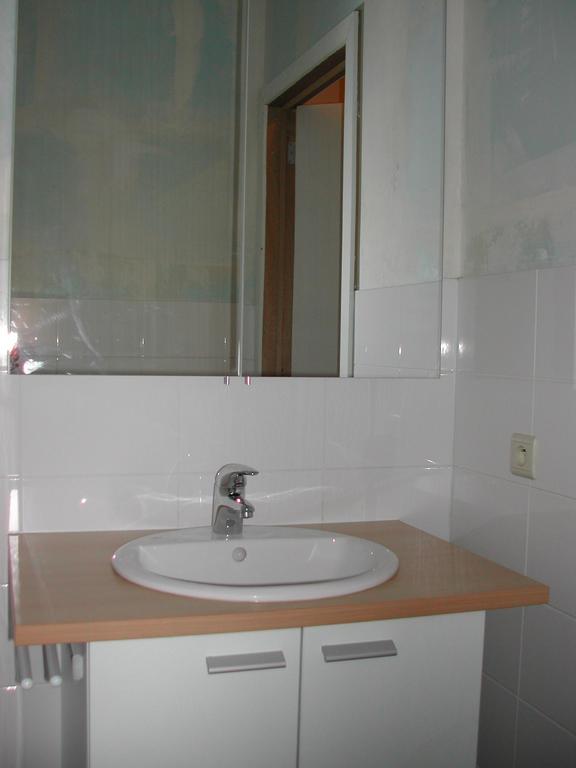 A small bathroom with a sink, mirror, and tiled walls.
