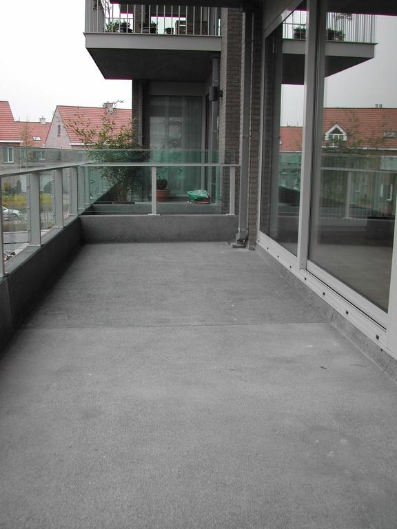 A spacious apartment terrace with glass railings and a concrete floor, photographed before moving in March 2003.