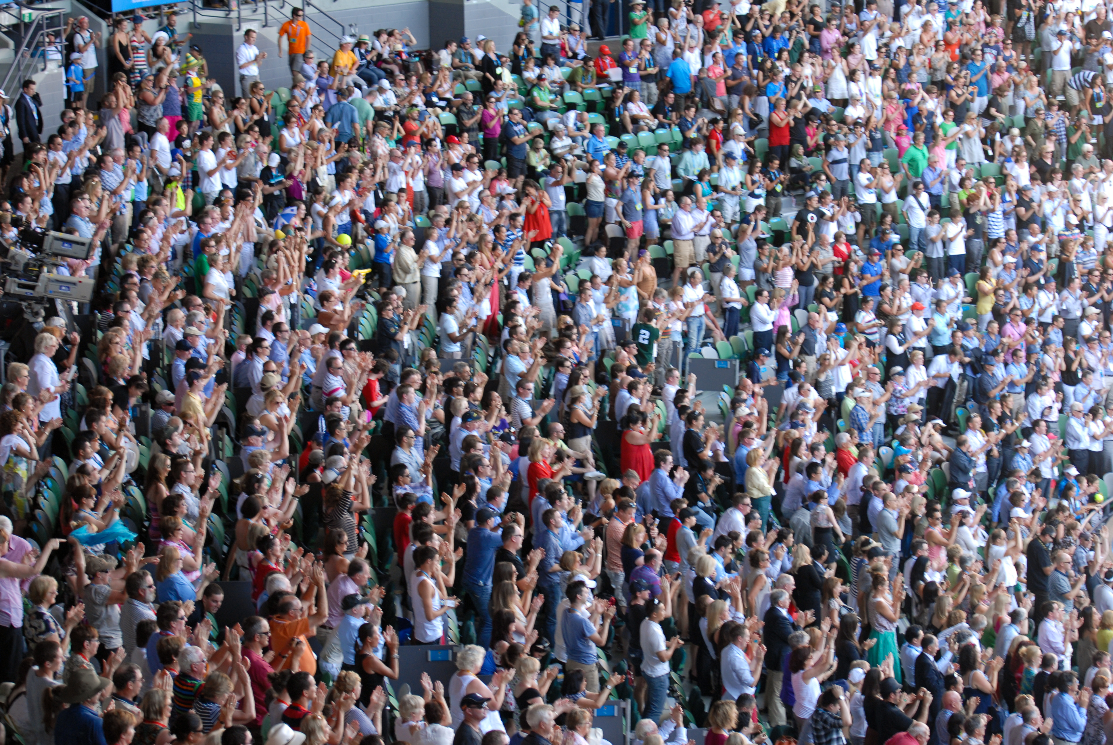 A large crowd of spectators stands and applauds during a match at the Australian Open 2012.