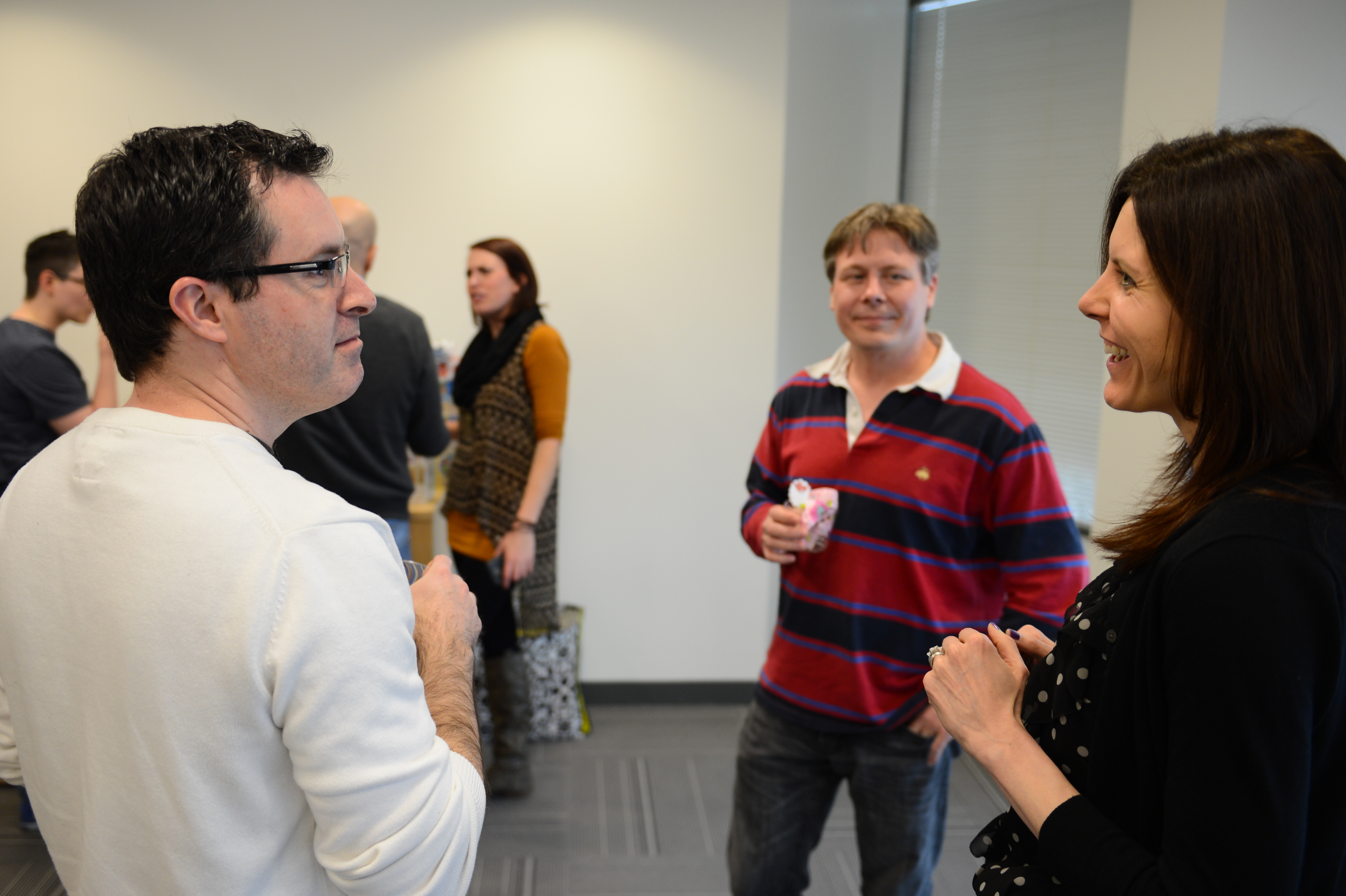 People chatting and smiling at a baby shower gathering in an indoor setting.