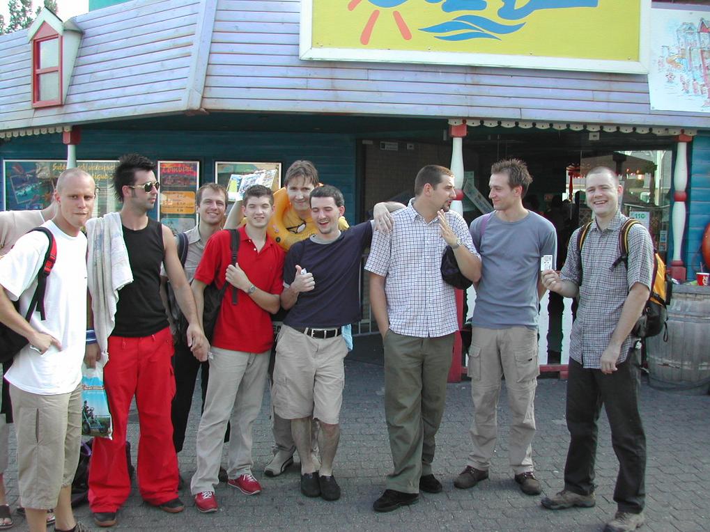 A group of young men posing together outside a themed attraction, smiling and interacting with each other.