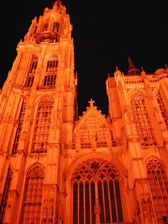A large, illuminated Gothic-style church tower and facade photographed at night from a low angle.
