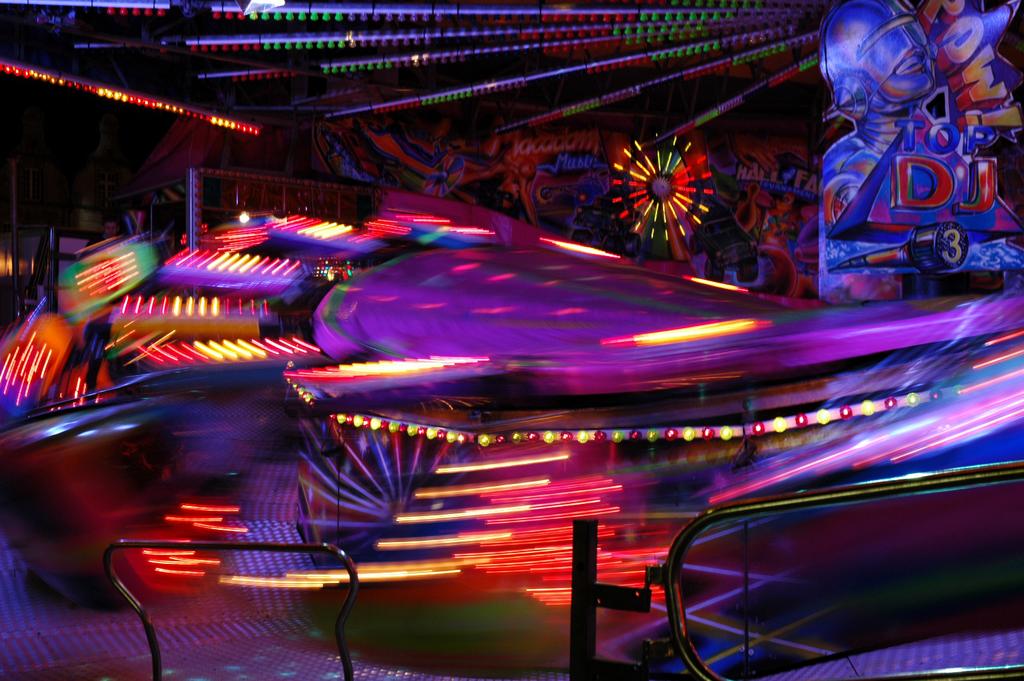 A spinning amusement park ride with colorful lights captured in motion at night.