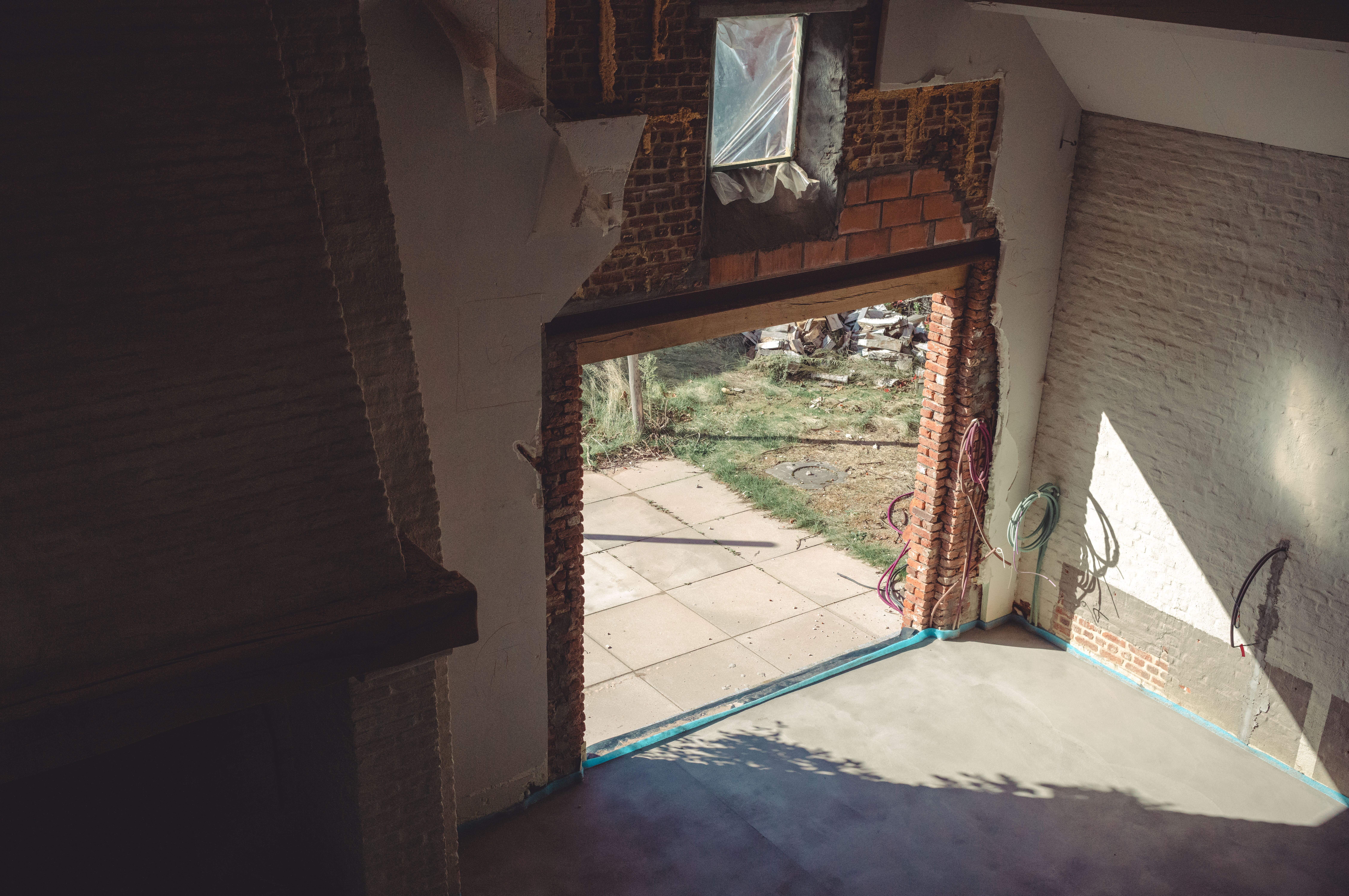 Partially constructed patio and kitchen area with sunlight streaming in through a large open doorway.