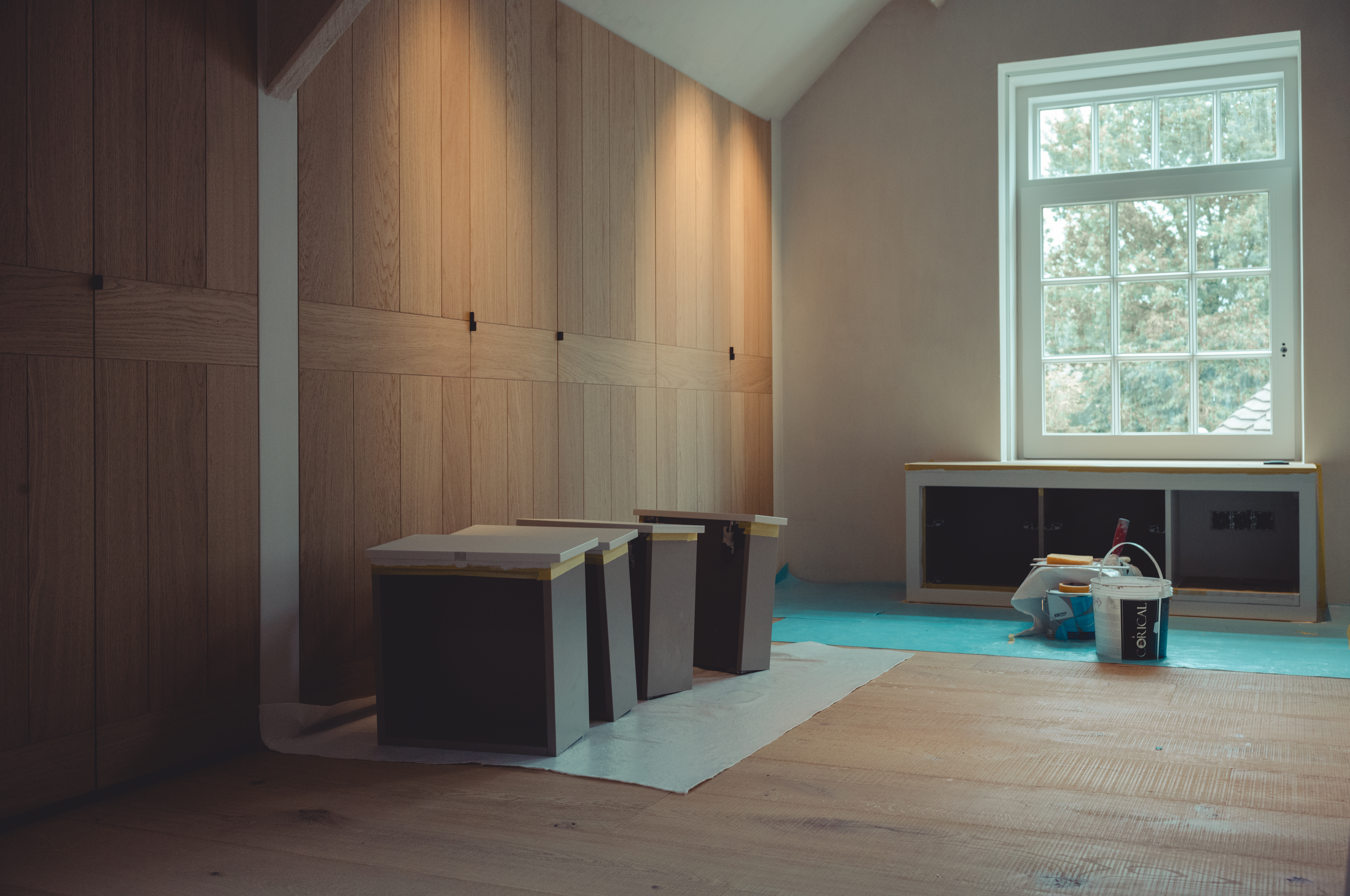 Built-in cabinets made out of oak with newly-painted drawers drying on the floor in front of them.