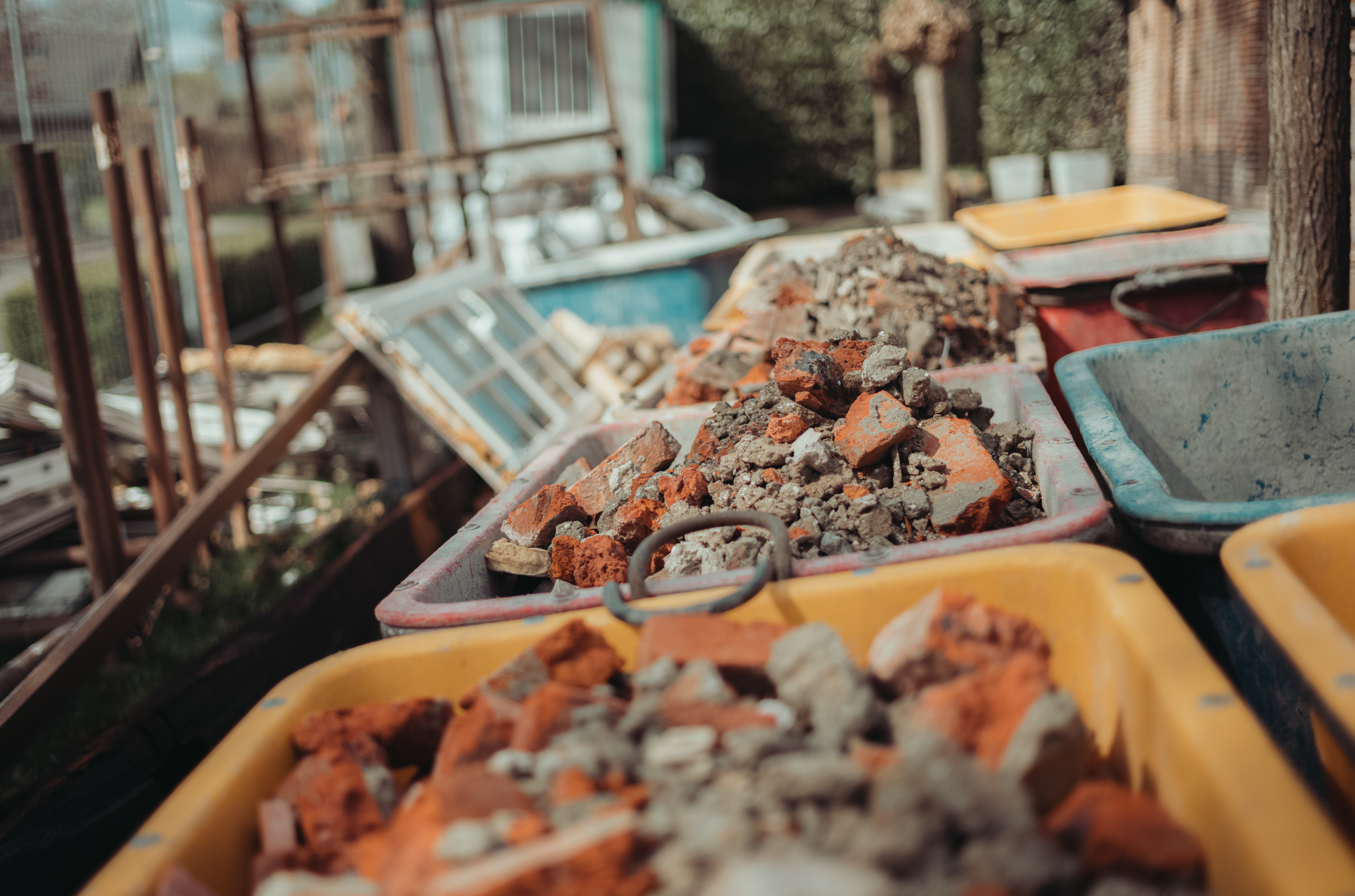 Several wheelbarrows filled with broken bricks and rubble from a demolition project, lined up outdoors.