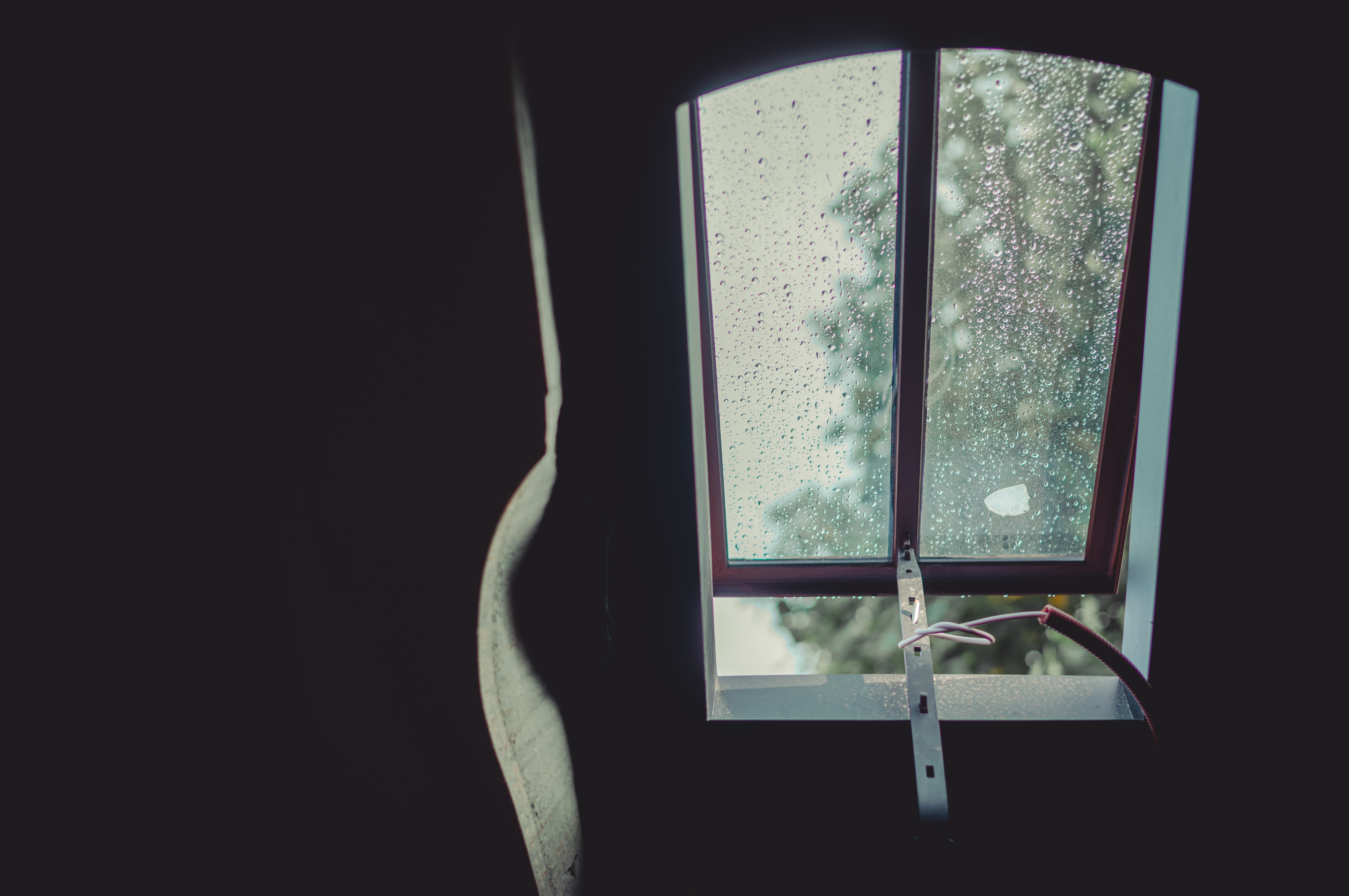 A wrought iron skylight with raindrops on the glass, partially open, replacing a modern Velux window.