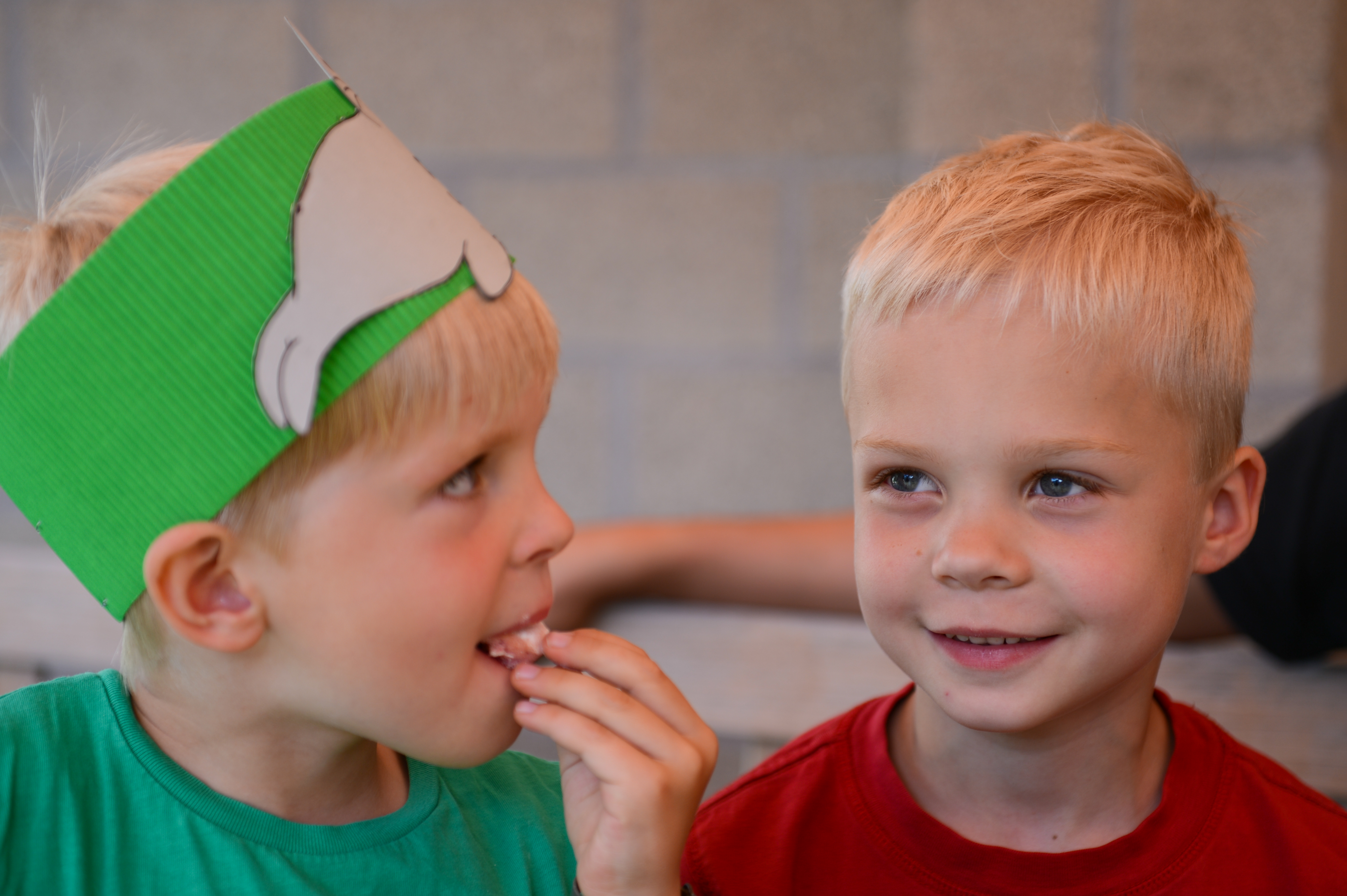 Two young children with blonde hair sit together.