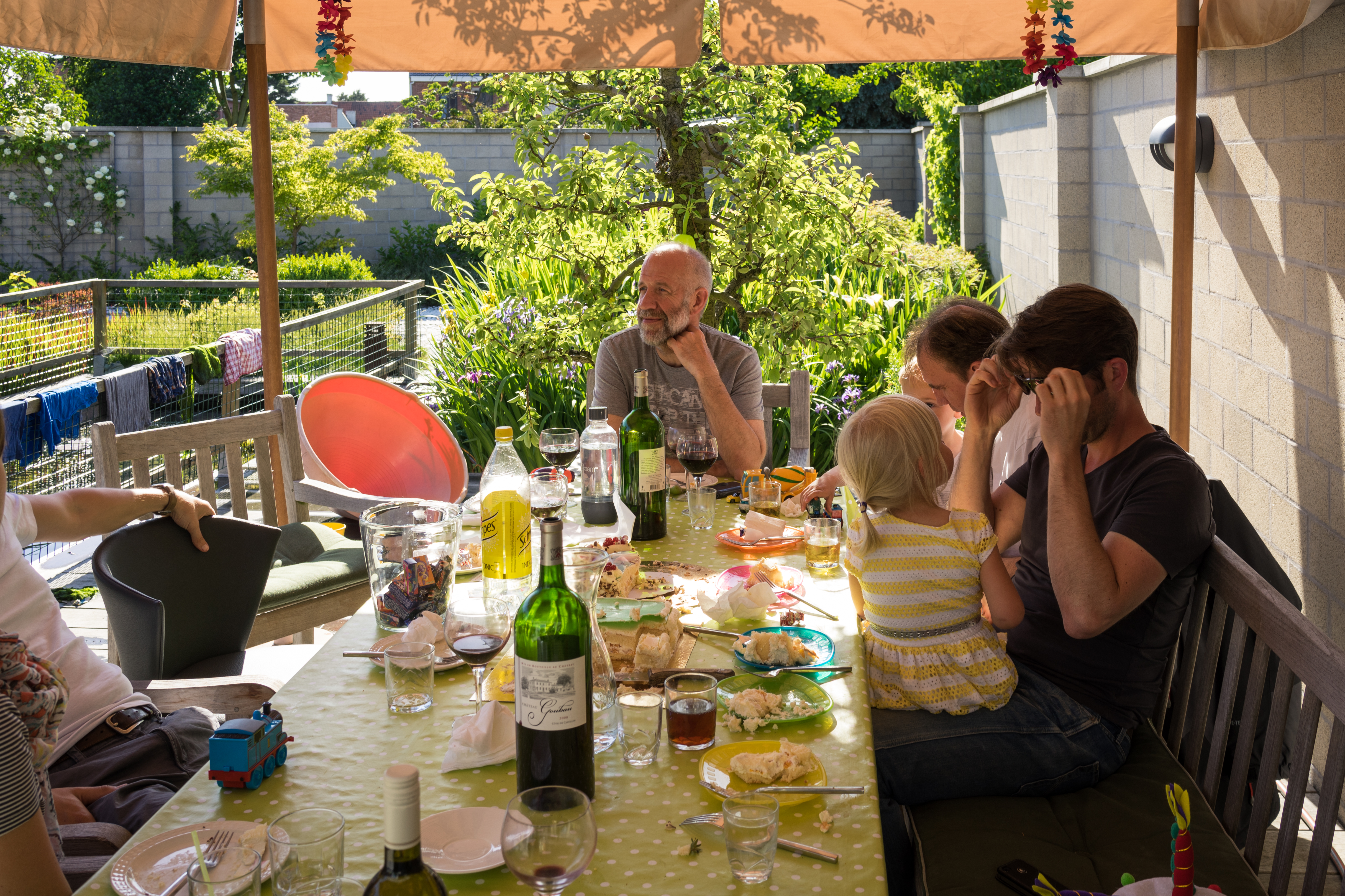 A group of people sits around a table outdoors, eating and talking.