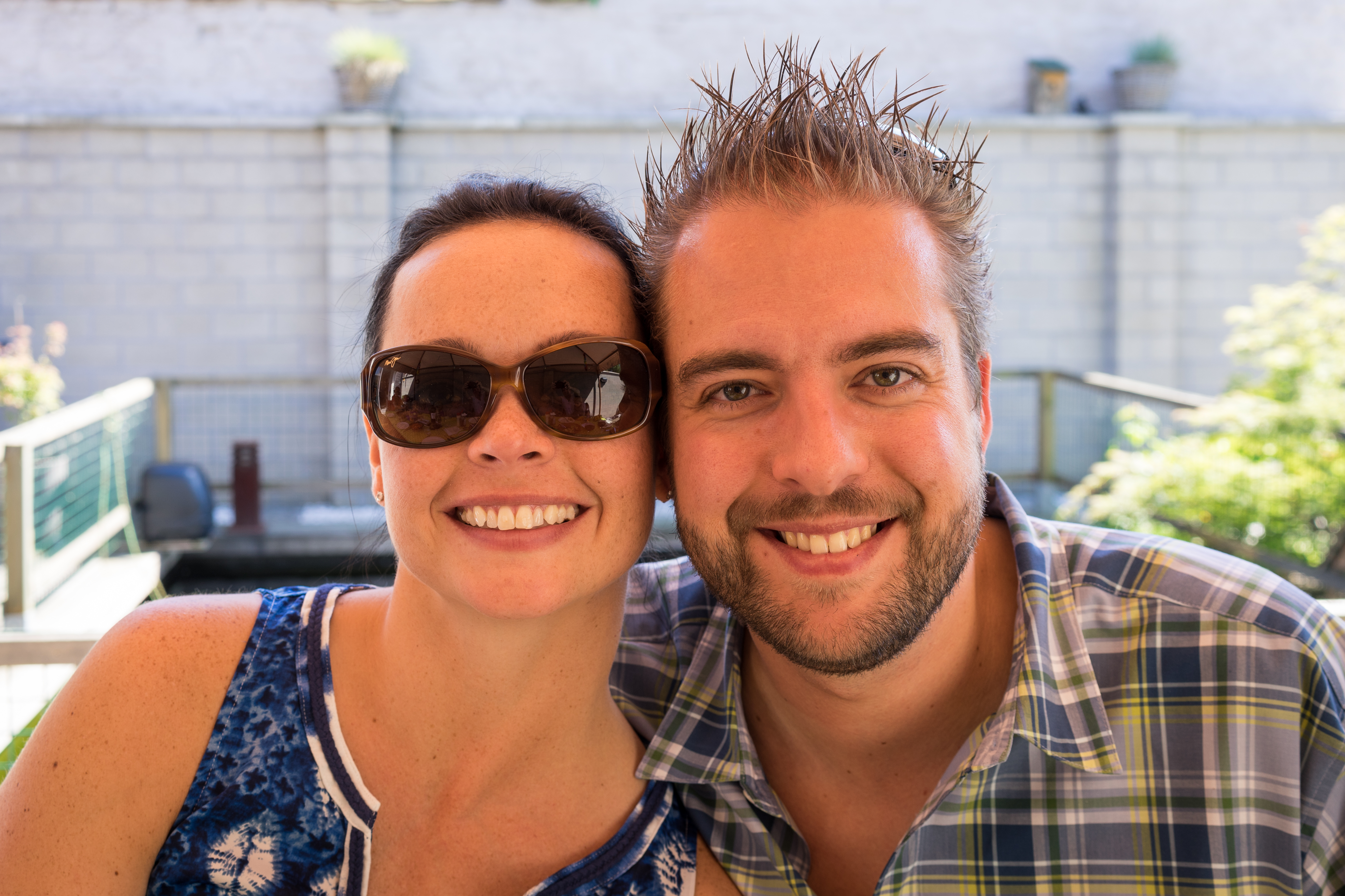 A smiling man and woman pose closely together at an outdoor party, looking at the camera.