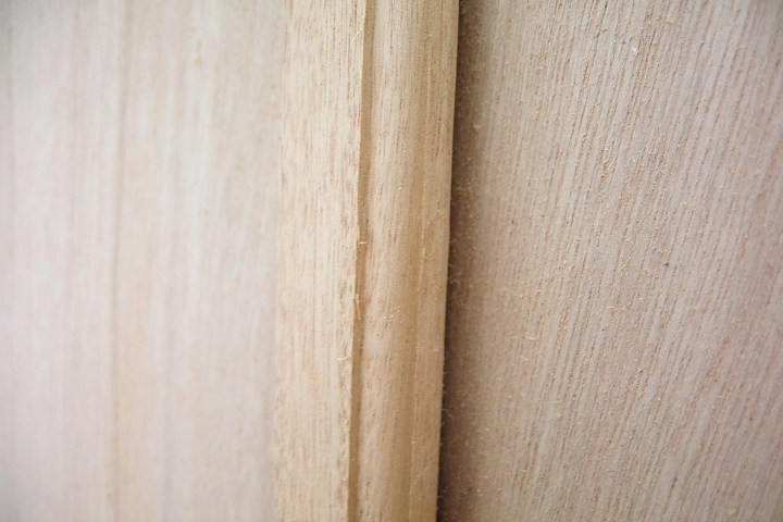 Close-up of a wooden boat panel with a joint, showing the texture and detail of the construction.