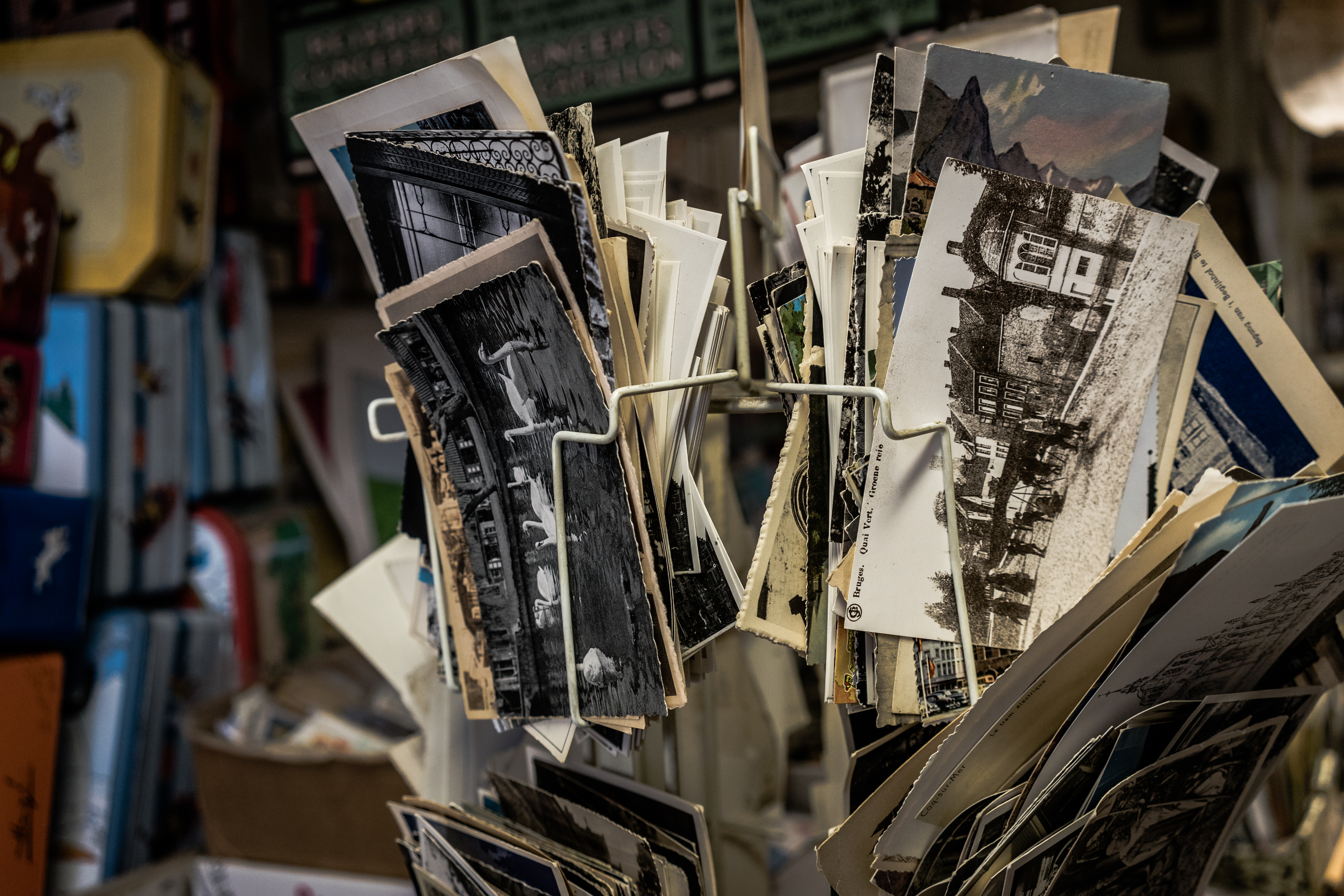 A rotating stand filled with vintage postcards, featuring black-and-white and color images of buildings, landscapes, and landmarks.