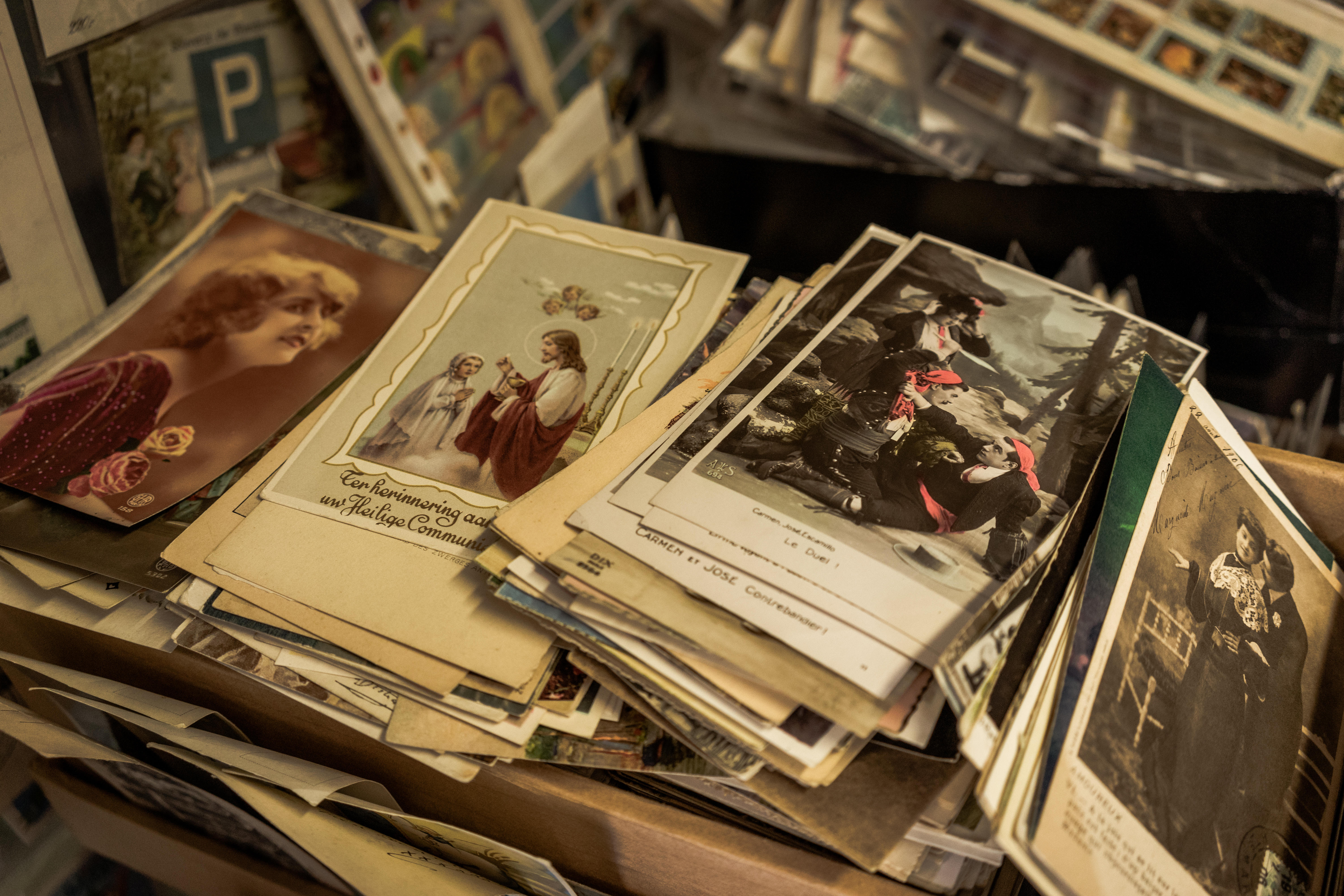 A box filled with antique postcards featuring vintage portraits, religious imagery, and historical scenes.