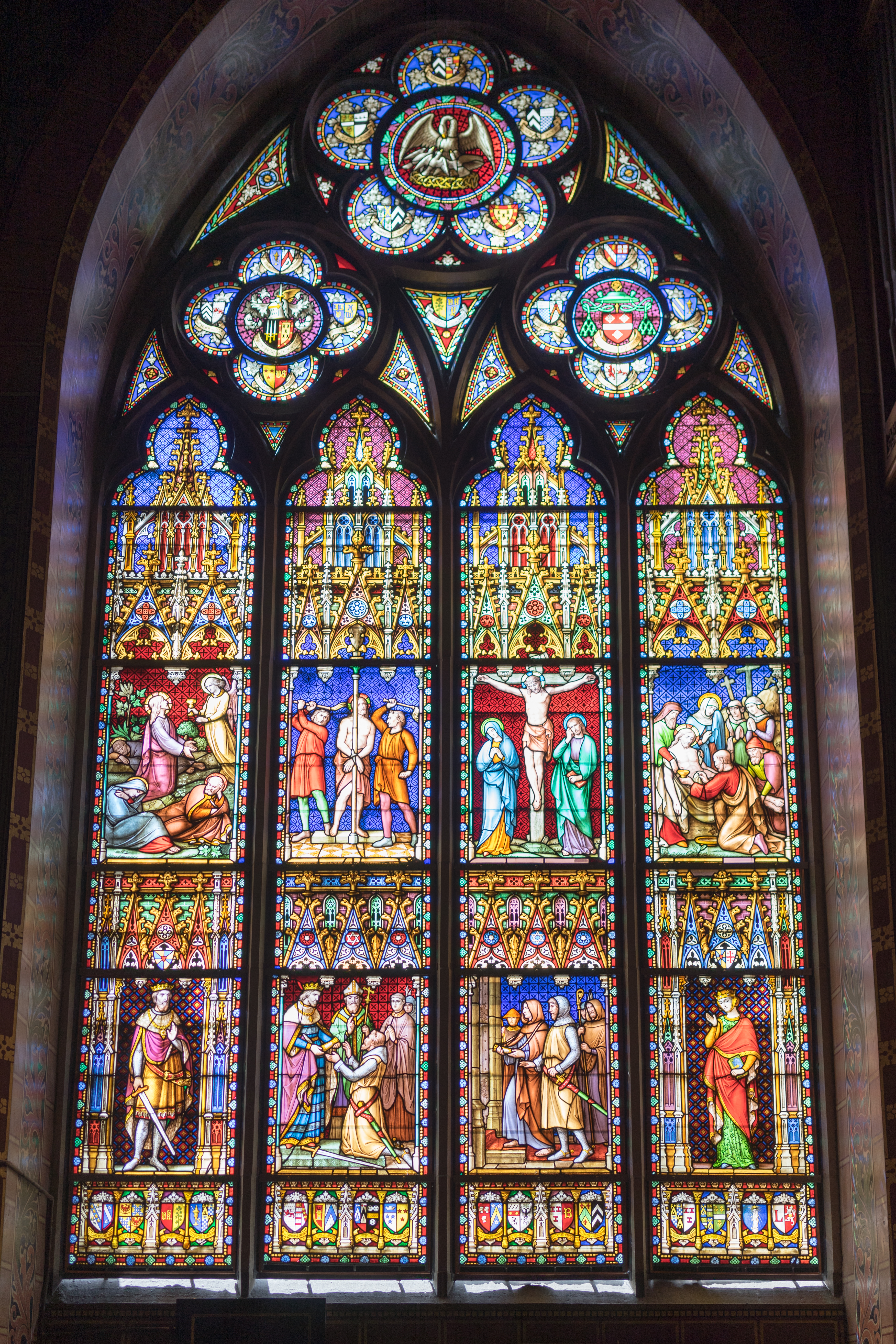 Stained glass window in the Basilica of the Holy Blood depicting biblical scenes, including the crucifixion of Jesus.