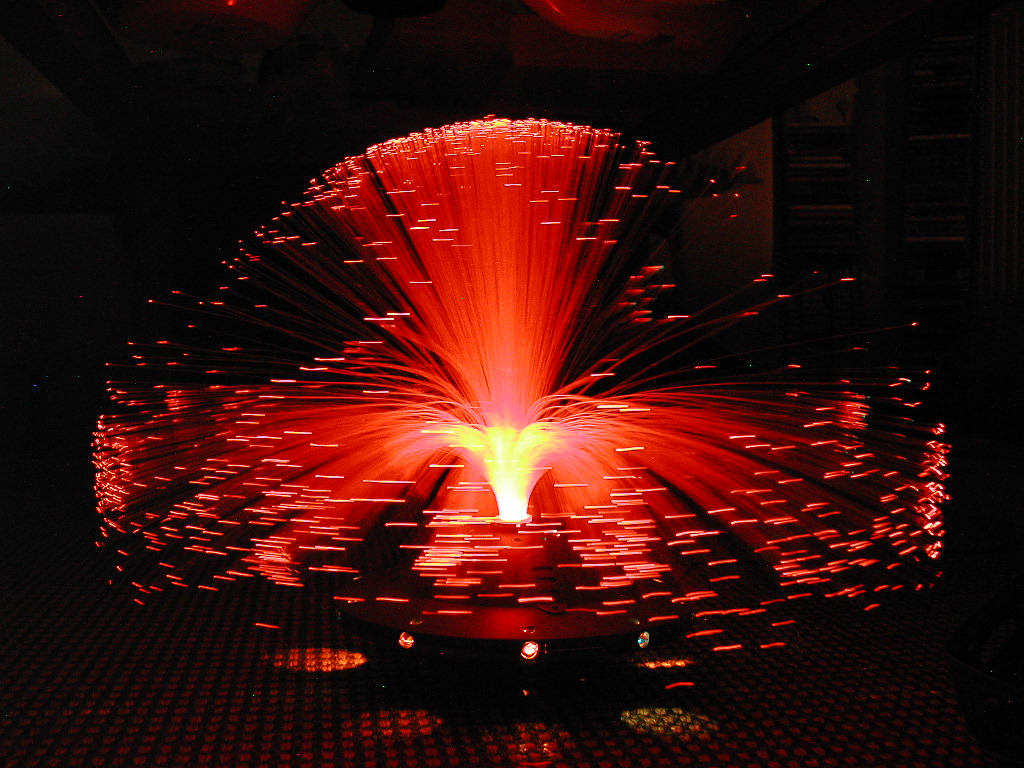 A glowing fiber optic lamp with red lights spreading outward in a dark room.