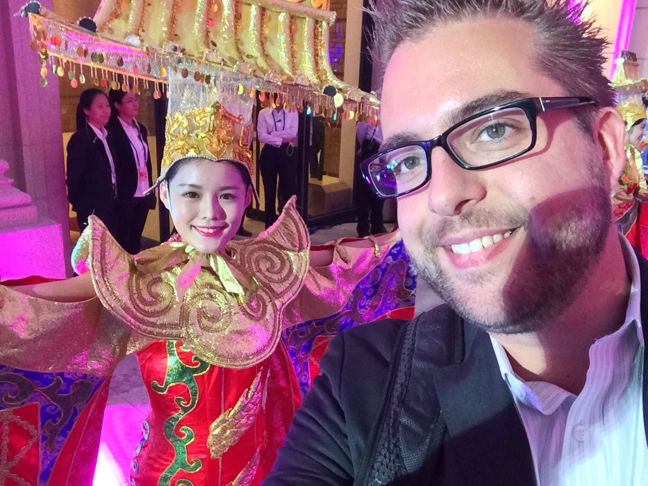 A man takes a selfie with a performer in a colorful traditional Chinese costume at the World Economic Forum event.