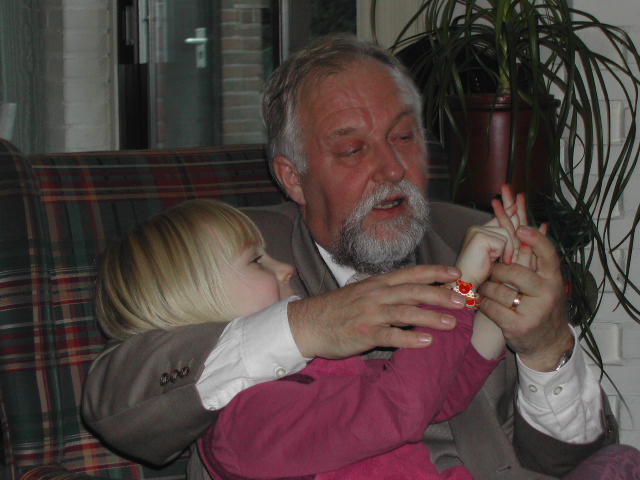 An older man and a young child sit together, playfully interacting with their hands.