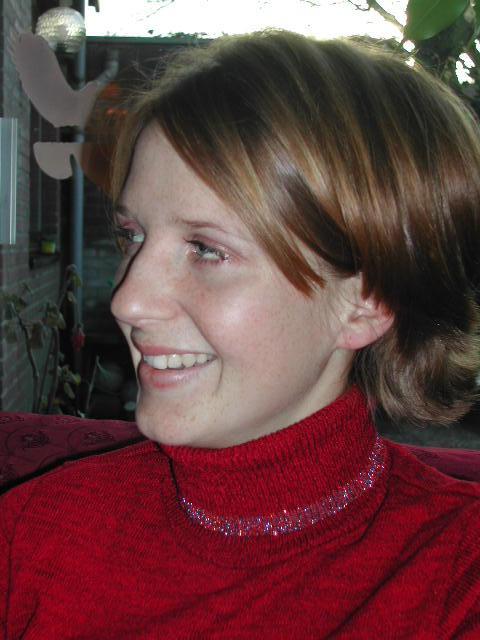 A person wearing a red turtleneck sweater smiles while looking to the side.