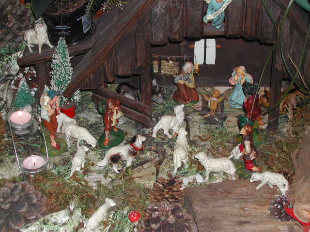 A nativity scene with figurines of shepherds, animals, and the Holy Family inside a wooden stable.