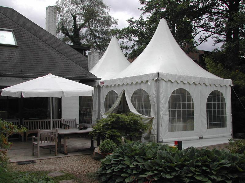 White event tents set up in a backyard with outdoor seating, likely prepared for a communion party.