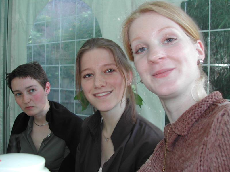 Three women sitting together, with one smiling at the camera in the foreground.