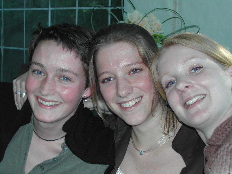 Three smiling people pose closely together for a photo at a communion party.