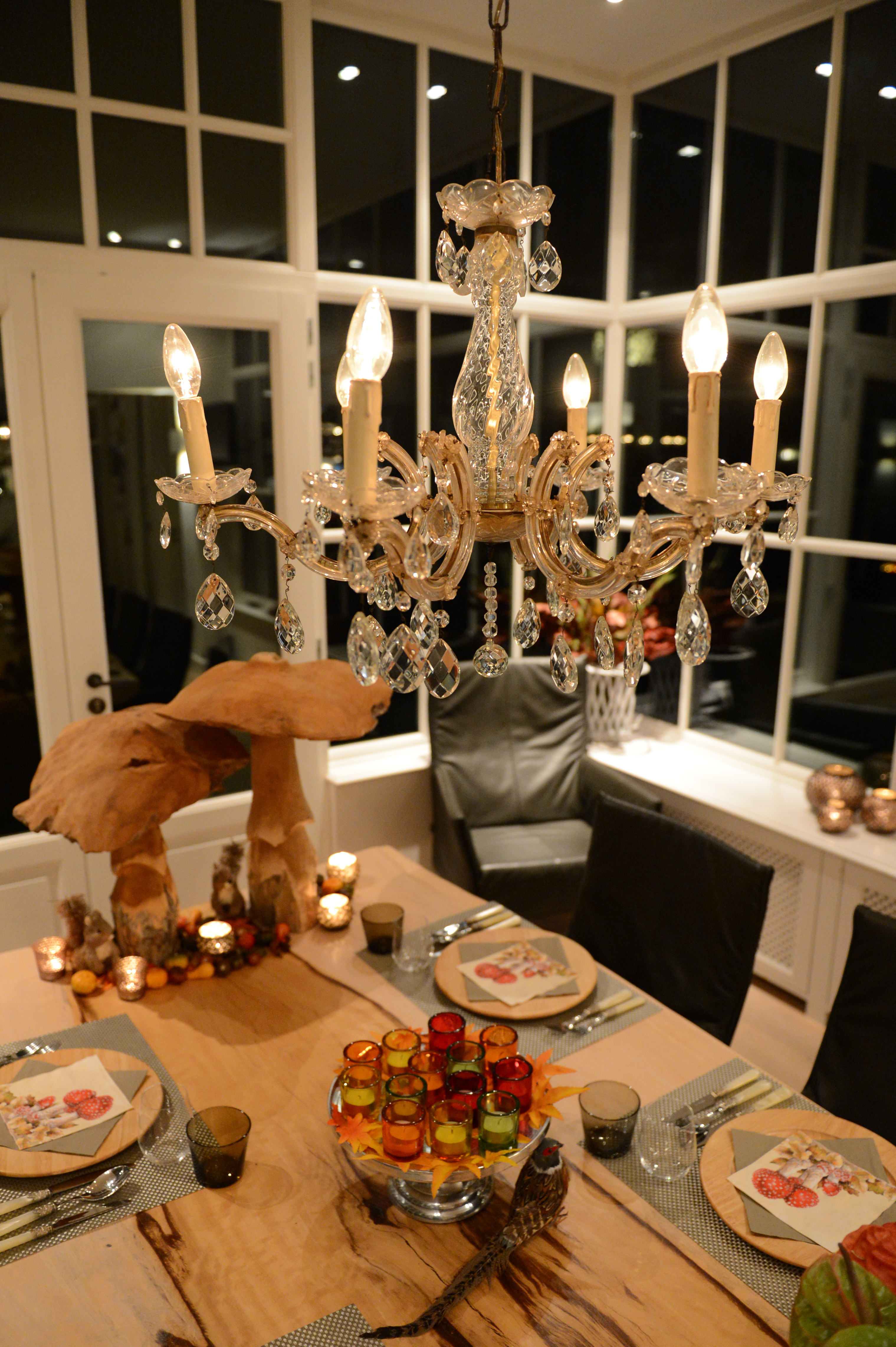 A decorated dining table with plates, glasses, and candles, set for a cooking class in a well-lit room.