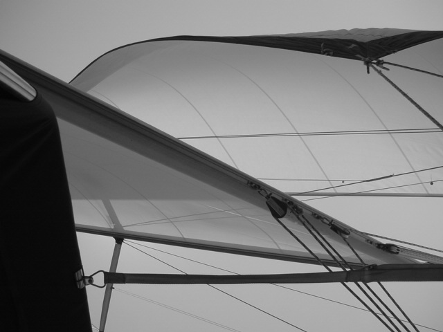Close-up of a sailboat's sails and rigging against the sky, showing the structure and tension of the fabric.