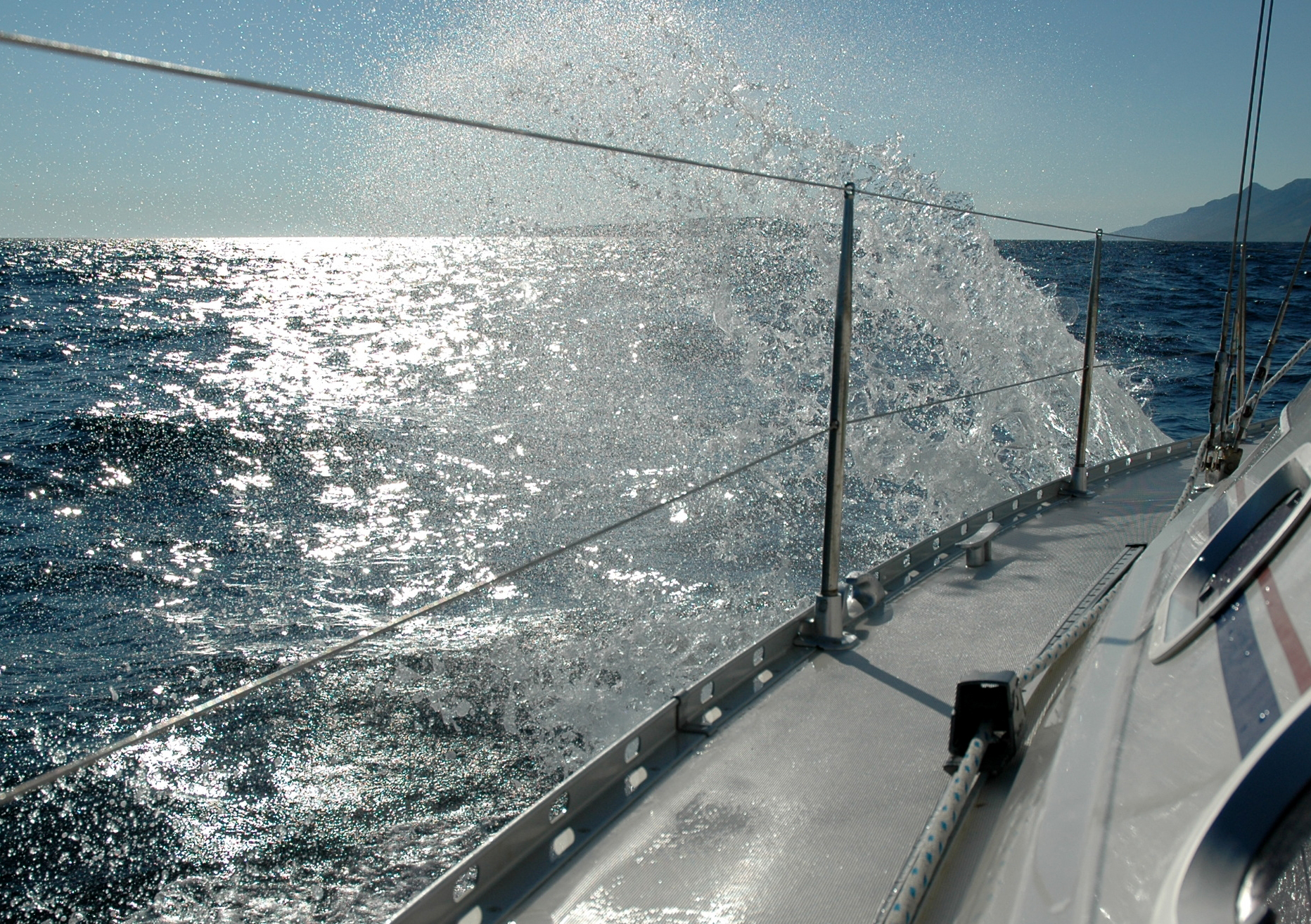 Water splashes against the side of a sailing boat as it moves through the open sea.