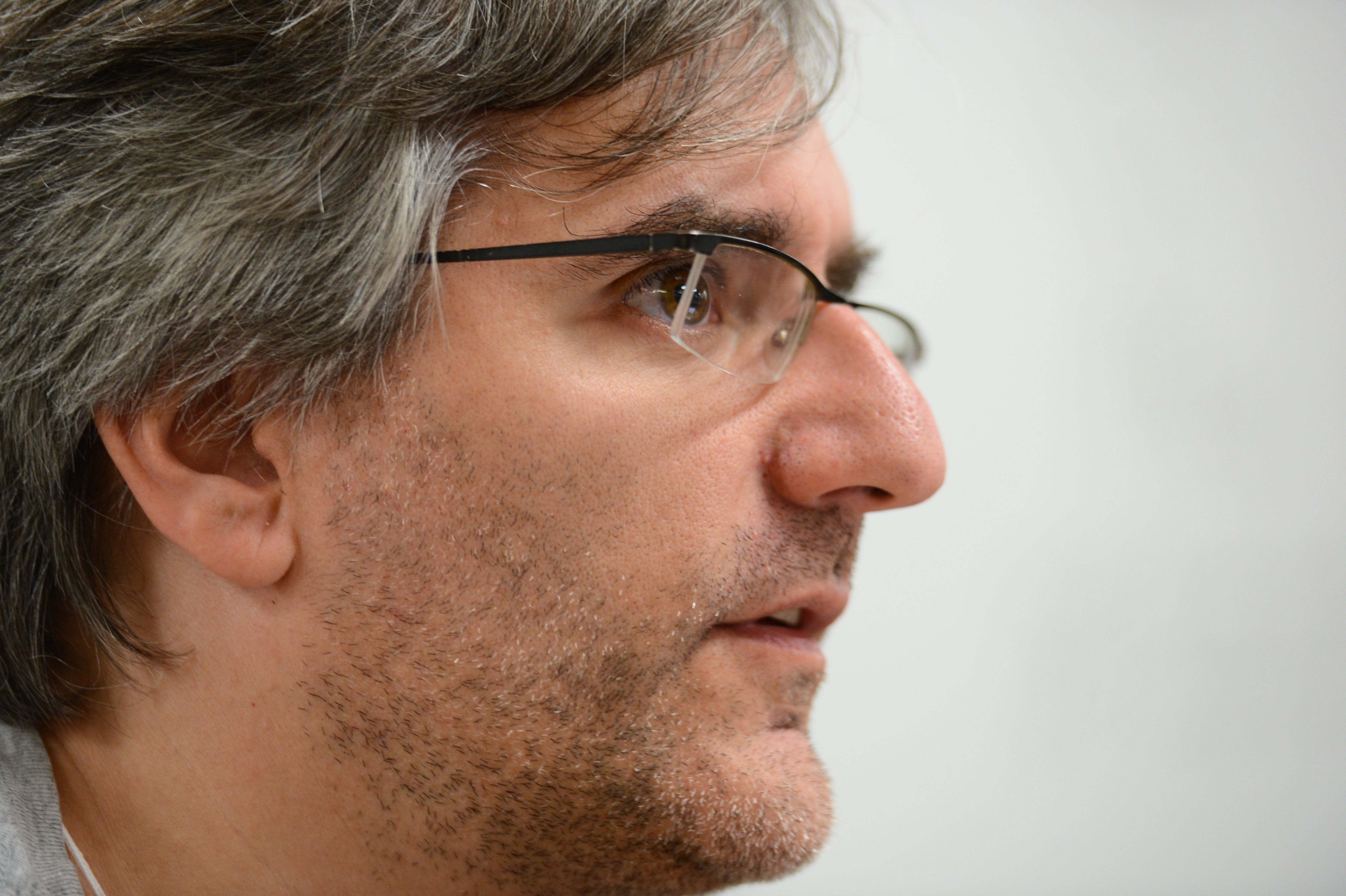 Close-up of a person wearing glasses, attentively listening or speaking during the Drupal Developer Summit sprint.