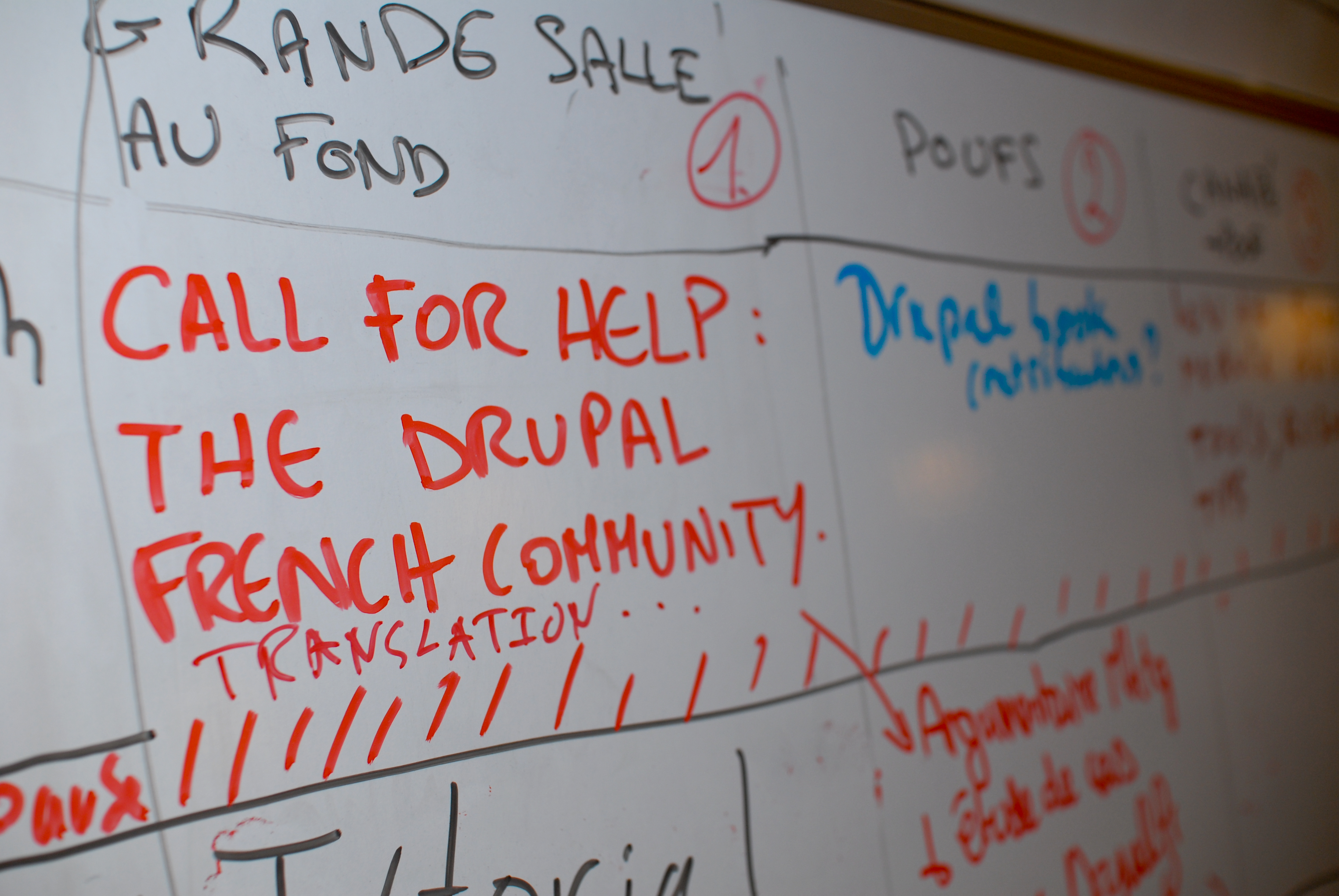 A whiteboard with "Call for help: The Drupal French community translation" written in red marker, requesting assistance.