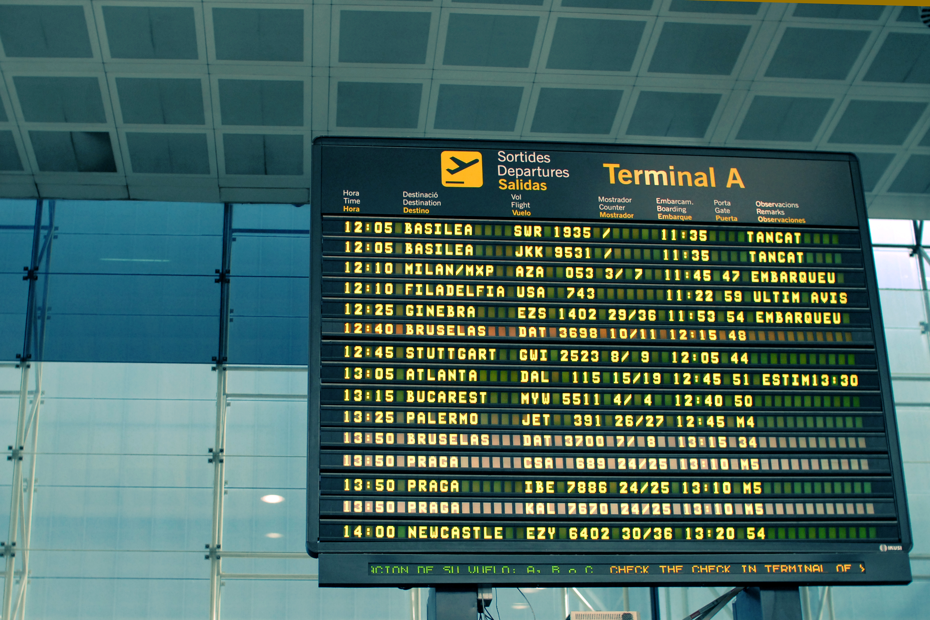 An airport departure board displaying flight times, destinations, and statuses at Terminal A in Barcelona.
