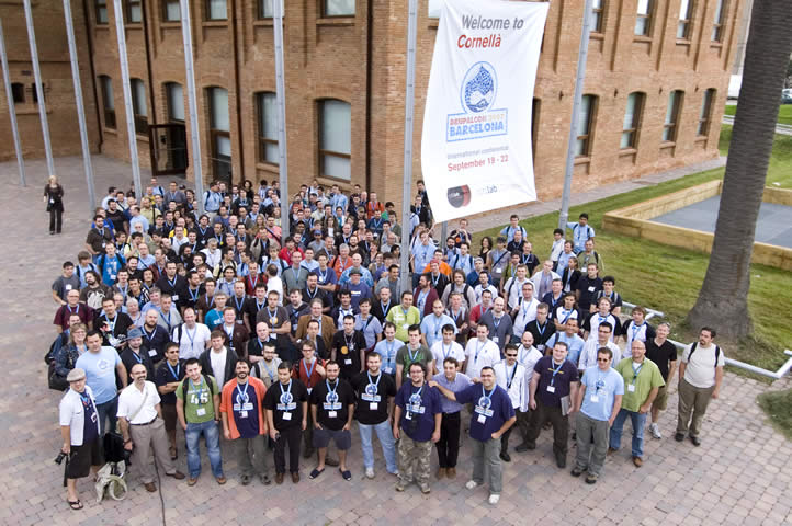 A large group of people posing for a photo at DrupalCon Barcelona 2007, standing outside a brick building.