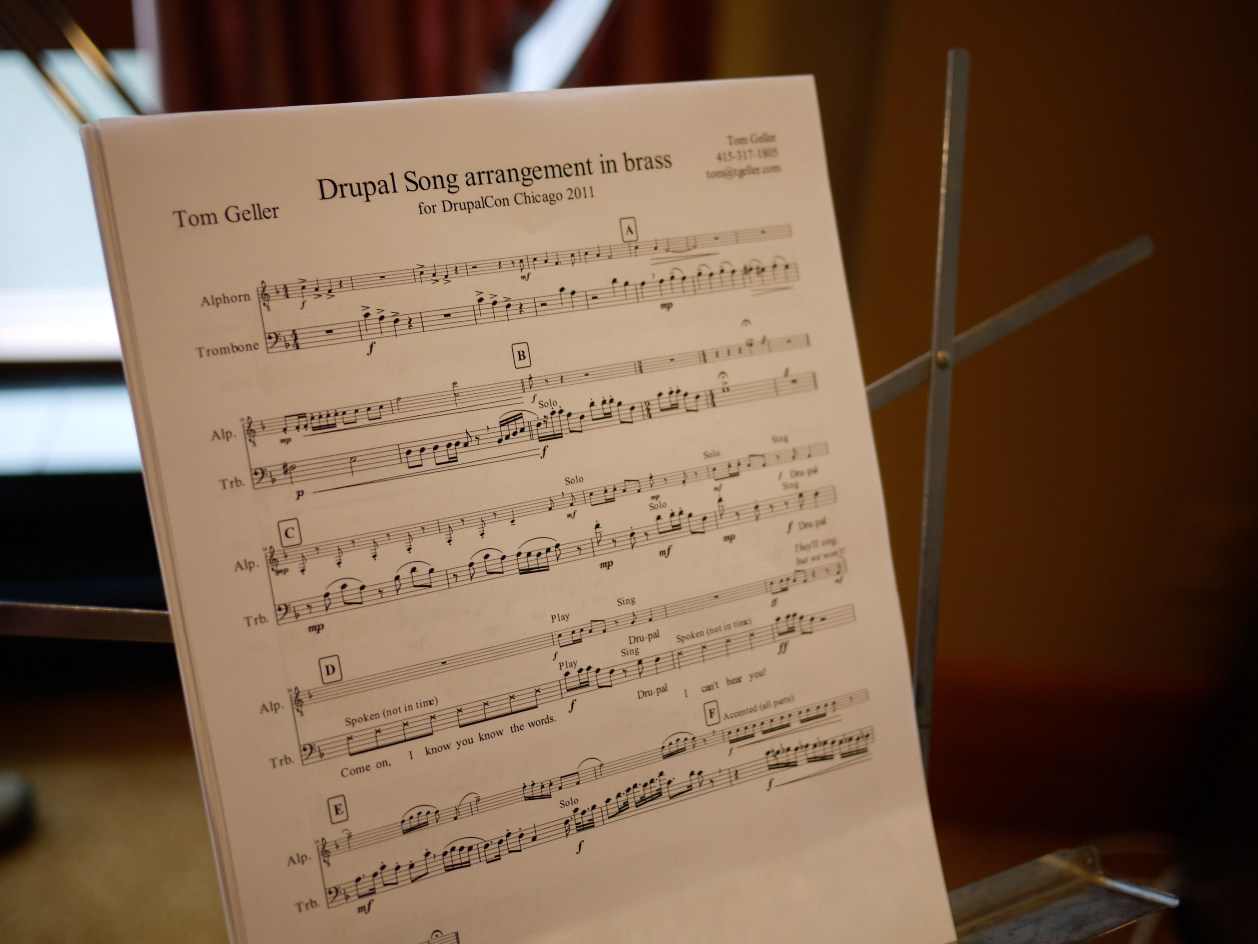 Sheet music titled "Drupal Song arrangement in brass" is displayed on a music stand at DrupalCon Chicago 2011.