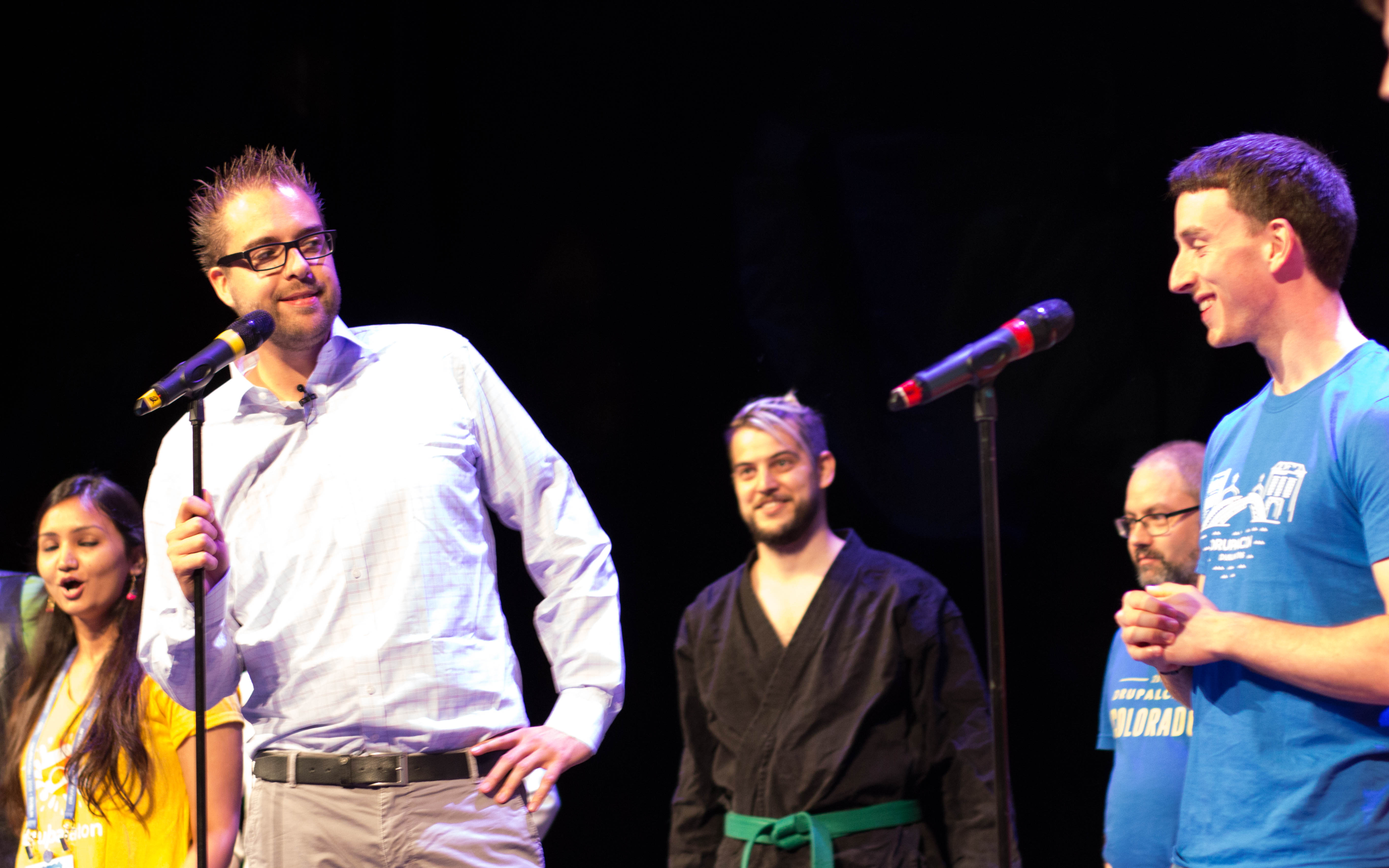 Several people stand on stage at DrupalCon Dublin 2016, speaking into microphones and engaging with the audience.