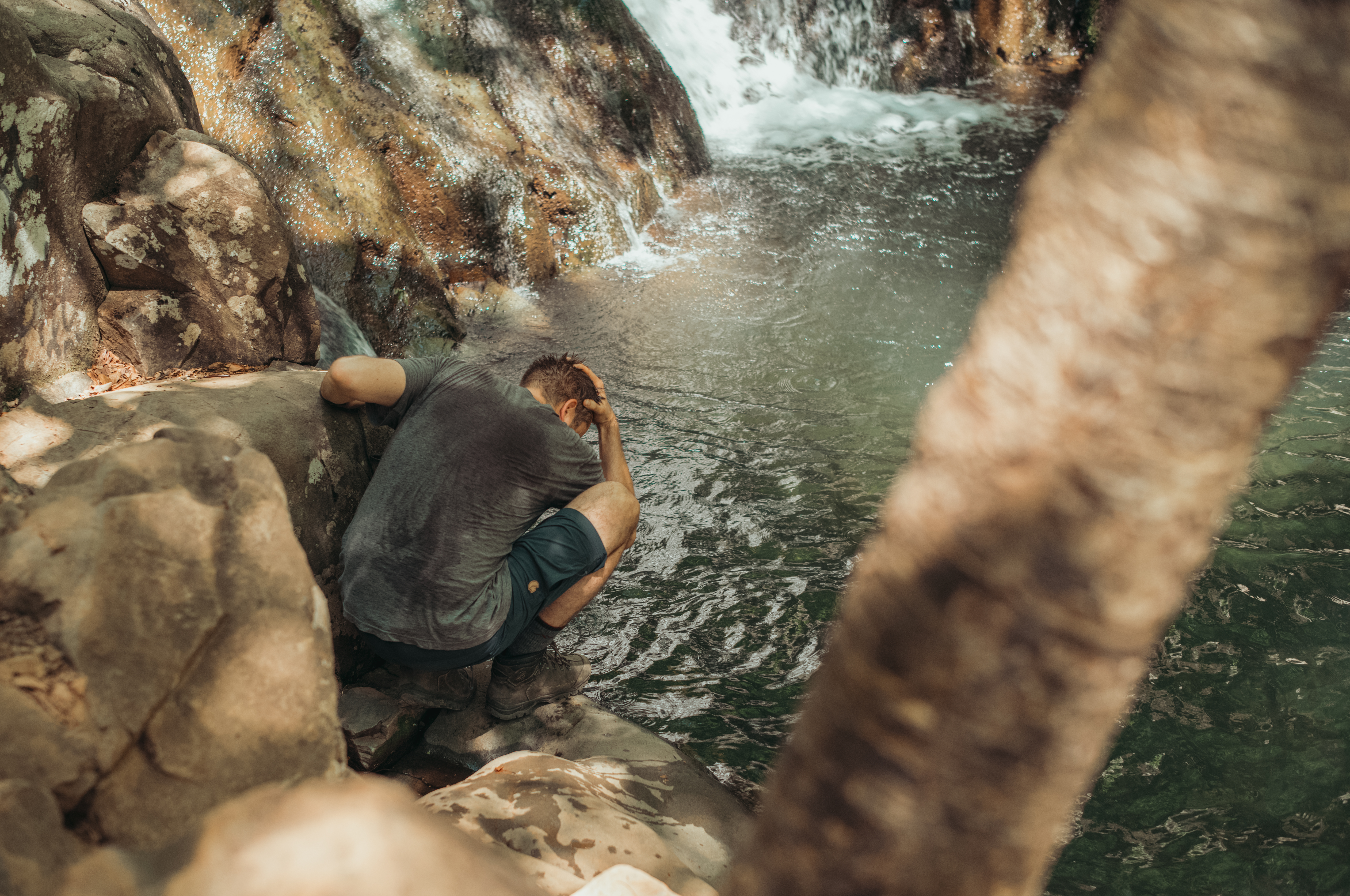 Man cooling off beside Rose River Falls in Shenandoah National Park during a hike on a hot day.