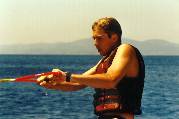 A person wearing a life vest holds onto a water ski rope over the ocean, preparing for activity.