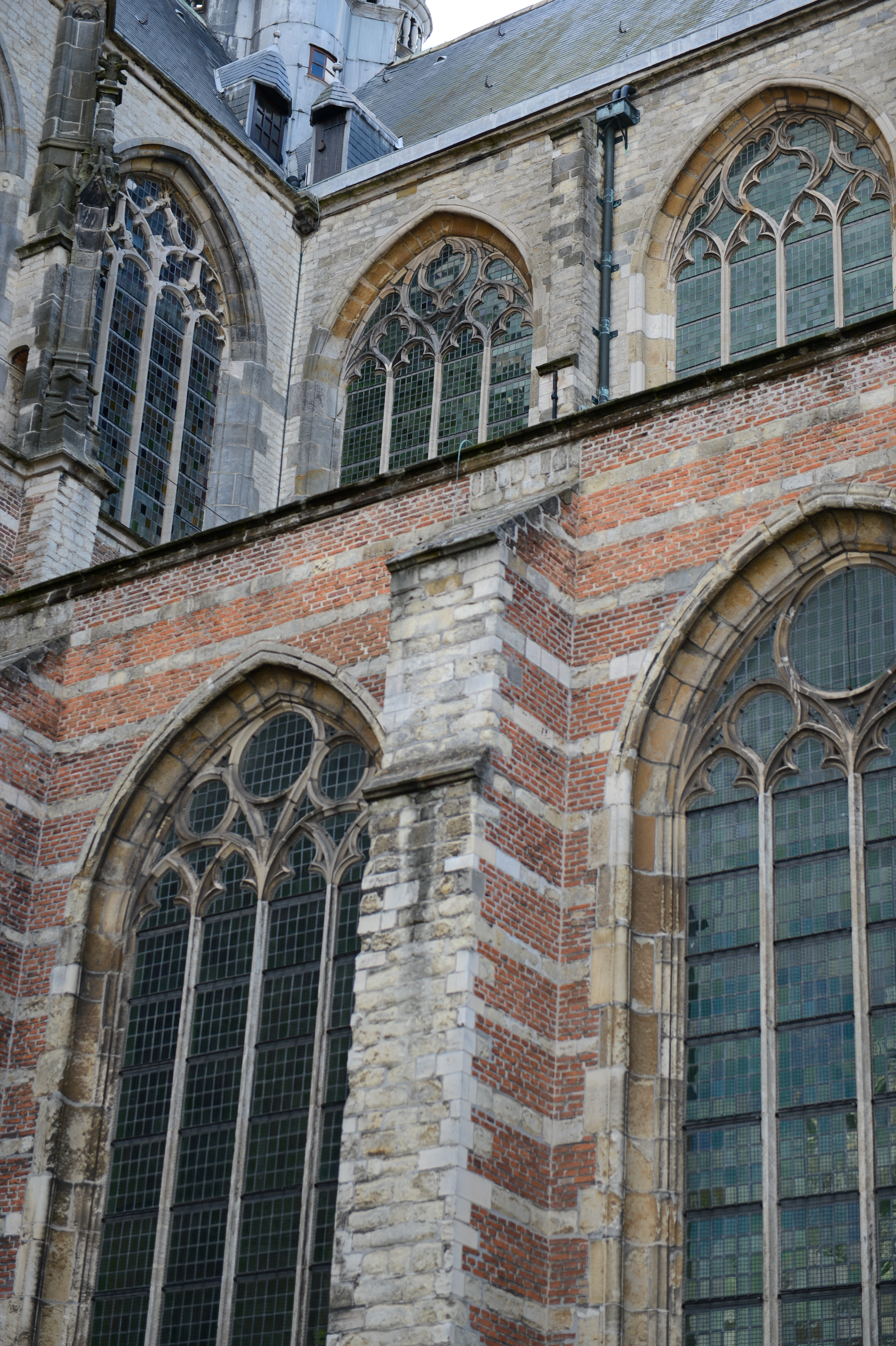 Close-up of a historic church with large arched stained-glass windows and a mix of brick and stone walls.