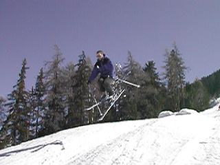 A skier in a purple jacket jumps in the air on a snowy slope.