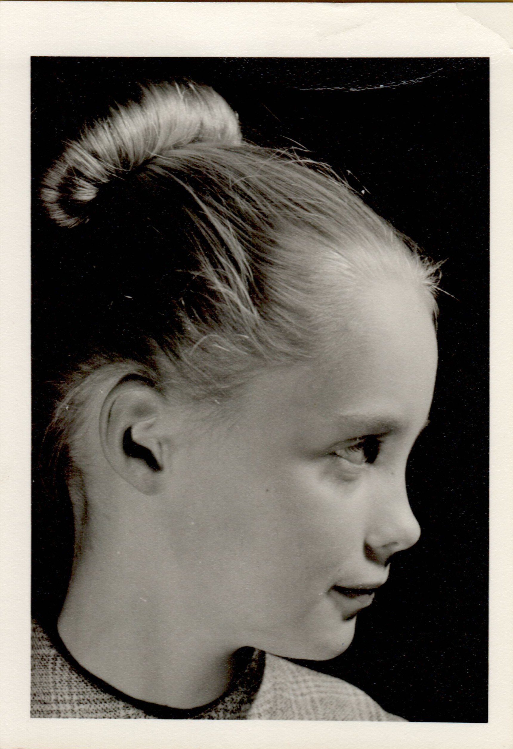 Black-and-white portrait of a young girl in profile, with hair in a bun, looking to the right.