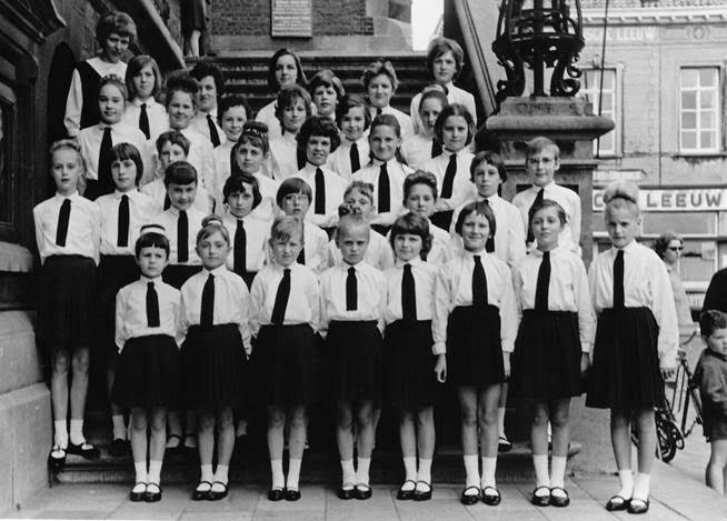 A group of young girls in matching uniforms stands on steps, posing for a group photo.