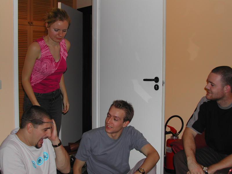 A group of friends laughs as one person reacts with surprise during a birthday party joke.