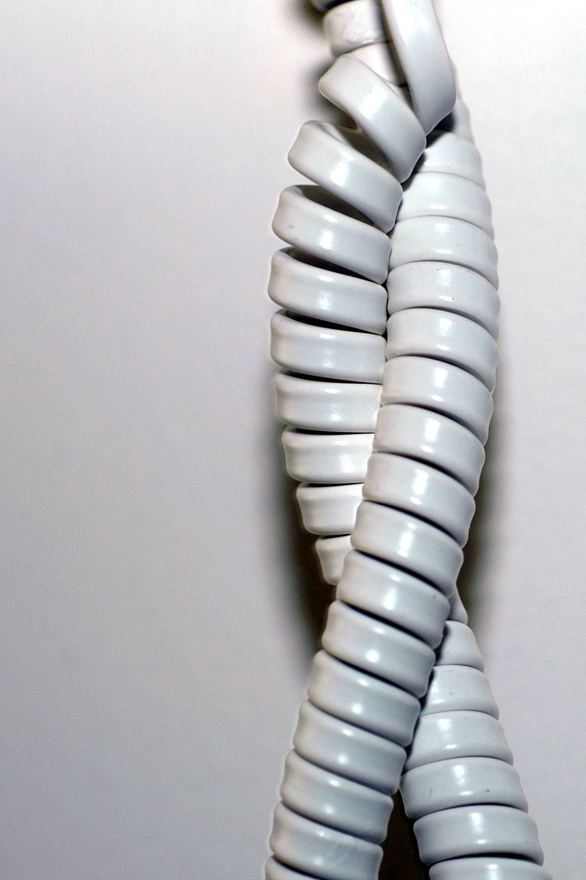 A close-up of a twisted, coiled telephone cord against a plain background.